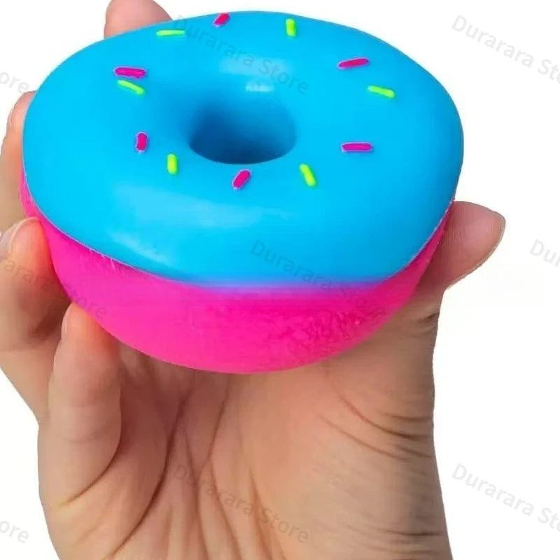 Blue donut stress toy with sprinkle dots, pink base, held in a hand